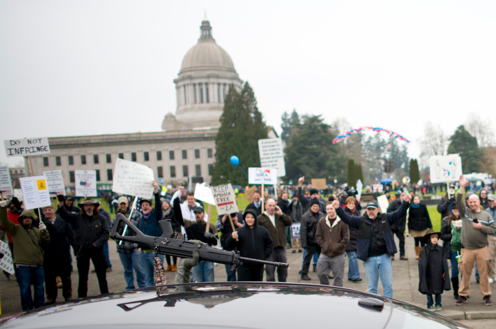 A gun supporter raises their gun through the passenger window while heading down Capitol Way as approximately 1,500 gun owners and enthusiasts attended the Guns Across America rally at the Washington State Capitol in Olympia Saturday, Jan. 19, 2013. The organization held events at capitol buildings in many states to show support for the 2nd Amendment and opposition to new gun control measures. Photo by Daniel Berman/www.bermanphotos.com